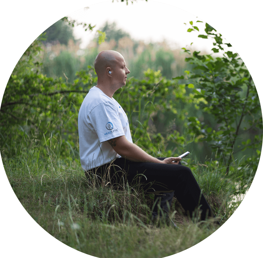 Ein Mann sitzt auf einer Wiese und meditiert. Es ist der Meditationsleiter Autor von Headletic