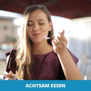 Frau mit langen Haaren sitzt an einem Tisch im Freien, genießt ihre Mahlzeit mit einer Gabel und sieht zufrieden aus. Der Text am unteren Rand lautet "Achtsames Essen.