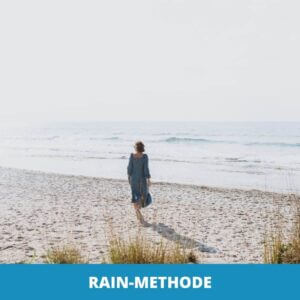 Eine Person in einem blauen Kleid spaziert allein an einem Sandstrand in der Nähe des Ozeans unter einem hellen Himmel, auf dem "RAIN-Methode" und das Headletic-Logo zu sehen sind.