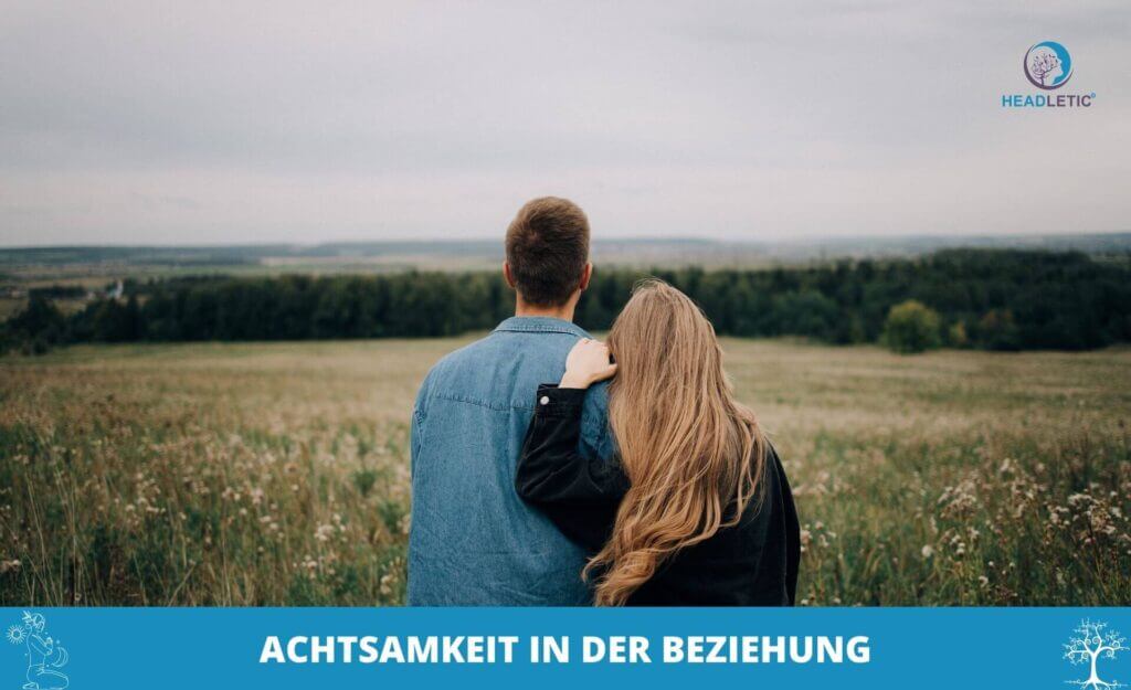 Ein Mann und eine Frau stehen auf einem Feld, die Frau hat ihren Kopf auf die Schulter des Mannes gelegt. Der Text am unteren Rand lautet: "Achtsamkeit in der Beziehung", um die Achtsamkeit in Beziehungen zu betonen.