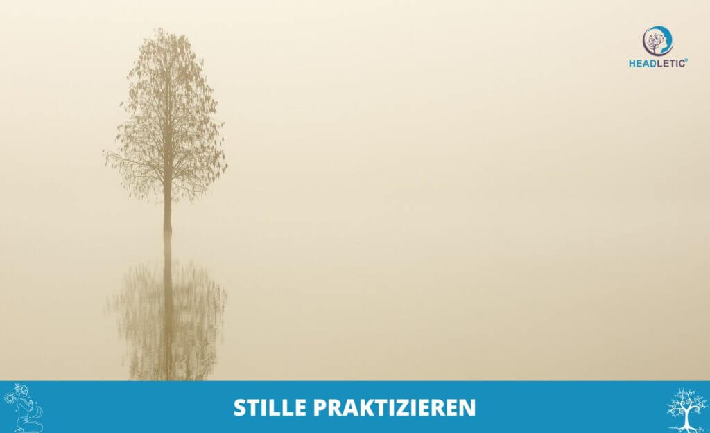 Ein einsamer Baum mit seiner Spiegelung steht in einer nebligen Landschaft. Ein blaues Banner am unteren Rand zeigt „STILLE PRAKTIZIEREN“ und das Logo „HEADLETIC“, das die Essenz des stillen Übens verkörpert.