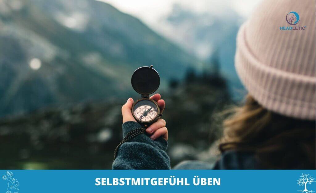 Person mit Kompass vor einer Berglandschaft, mit Strickmütze, mit dem Text "Selbstmitgefühl üben" und einem HeAdLetic Logo oben rechts - eine Erinnerung daran, wie wichtig es ist, Selbstmitgefühl zu üben.